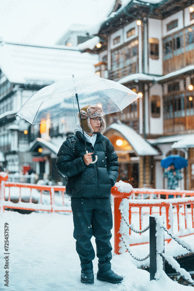 man tourist Visiting Ginzan Onsen in Yamagata, happy Traveler sightseeing Japanese Onsen village with Snow in winter season. landmark and popular for attraction in Japan. Travel and Vacation concept