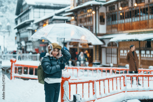 Woman tourist Visiting Ginzan Onsen in Yamagata, happy Traveler sightseeing Japanese Onsen village with Snow in winter season. landmark and popular for attraction in Japan. Travel and Vacation concept