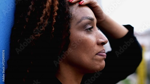 One anxious black woman in 50s feeling overwhelmed by life feeling stress and worry during difficult times, tight close-up face of pensive contemplative expression photo
