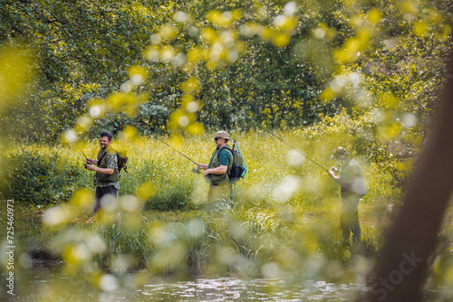 Senior and young fishermen on river shore having fun fishing and talking. Concepts of enjoyment and recreation in nature.