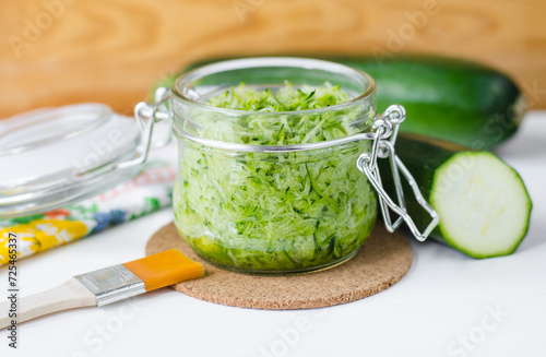 Fresh grated zucchini in a glass jar. Ingrediet for preparing homemade face or hair mask, natural beauty treatment and spa recipe. photo