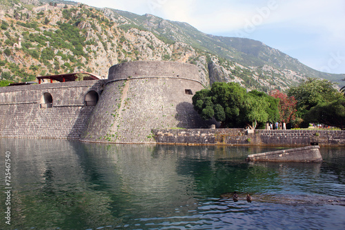 Water ditch in front of the fortress wall. Old town of Kotor. Mountains behind