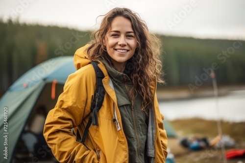 Portrait of a smiling young woman hiker standing in front of tent