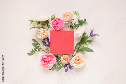 Overhead view of roses, chrysanthemums and alstroemeria flowers arranged around a blank pink card photo