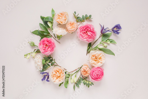 Overhead view of a circular Floral arrangement of roses, chrysanthemums, alstroemeria flowers and foliage on a pink background photo