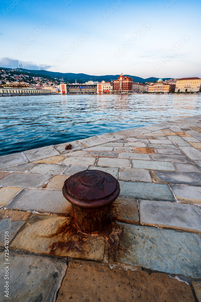 Naklejka premium Dusk and night in Trieste. Between historic buildings and the sea.