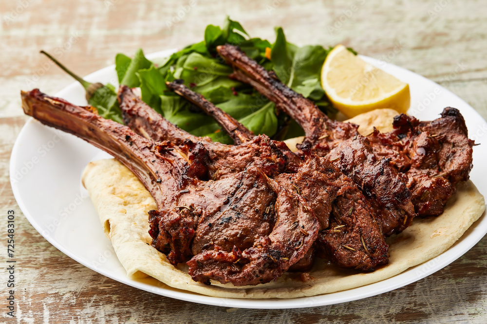 Grilled Lamb Chops with lemon slice ad salad served in dish isolated on table top view of arabic food