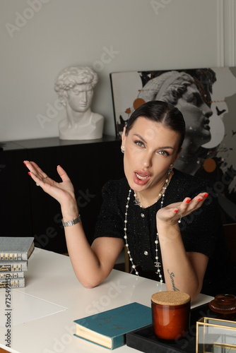 Serious business woman officially dressed in black twid dress. Beautiful  Office manager work at the table with books,  cup of tea. Lady portrait. Bookshelf photo