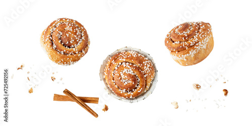 Fresh baked cinnamon buns kanelbulle with crumbs flying falling isolated on white background.
