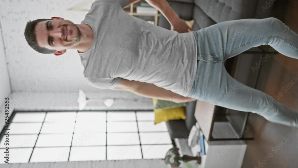 A young hispanic man dancing joyfully indoors in a stylish living room, showcasing energy and happiness. A young hispanic man dancing joyfully indoors in a stylish living room, showcasing energy and happiness.