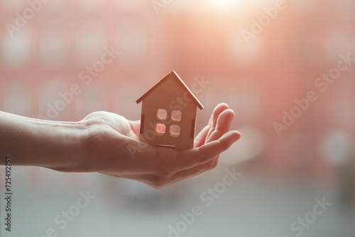 Real estate agent's hand holding wooden house model from natural material, buy sell, rent and best offer,  finding your new home concept