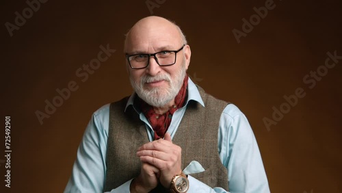 A man with a knowing smile clasps his hands together, hinting at a clever stratagem with a playful glint in his eye against a warm, dark backdrop. Camera 8K RAW. 