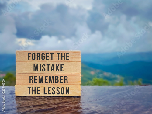 Inspirational life quote. Forget the mistake, remember the lesson text on wooden blocks with nature background. Stock photo.