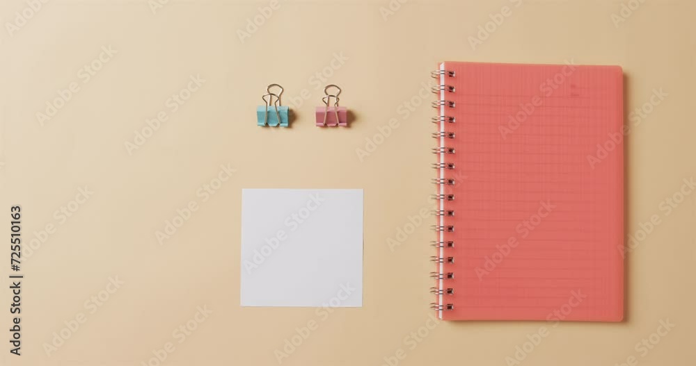Overhead view of red notebook and school stationery arranged on beige background, in slow motion Overhead view of red notebook and school stationery arranged on beige background, in slow motion