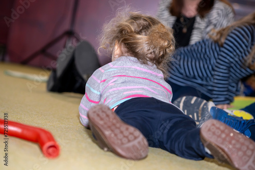 petite fille blonde allongée au sol sur une moquette dans un salon photo