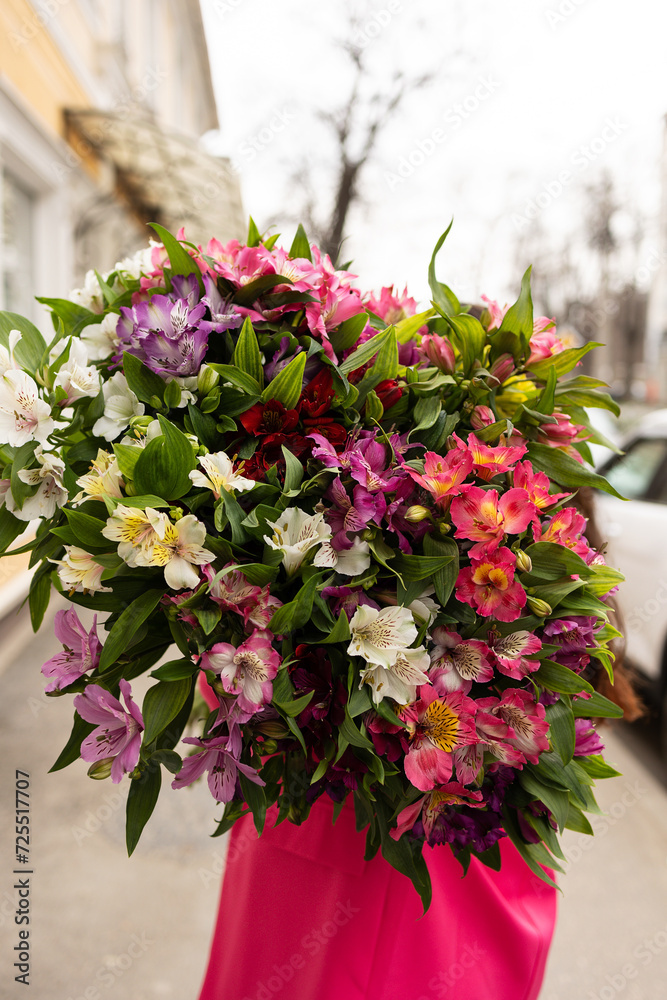 View from the back, a large bright bouquet of colorful alstroemerias on the street, selective focus. Mother's Day Holiday Gift, International Women's Day, Valentine's Day