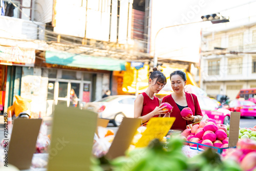 Happy Asian family celebration Chinese Lunar New Year festival together. Mother and daughter choosing and buying fresh fruit orange for celebrating Chinese New Year at Chinatown street market. © CandyRetriever 