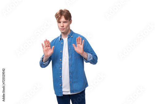 young well-groomed caucasian red-haired man in a denim shirt actively gesticulates photo