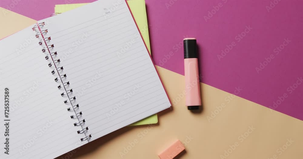 Overhead view of open notebook with school stationery on beige and purple background, in slow motion Overhead view of open notebook with school stationery on beige and purple background, in slow motion
