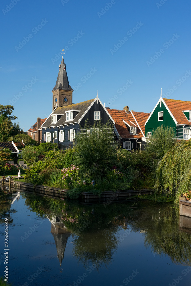 View of the beautiful and typical fishing village of Marken in Netherlands at sunset reflected on a canal.