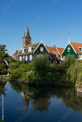 View of the beautiful and typical fishing village of Marken in Netherlands at sunset reflected on a canal.
