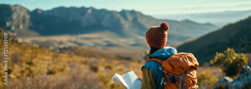 woman in outdoor gear hiking in a mountainous carrying books and a portable study setup