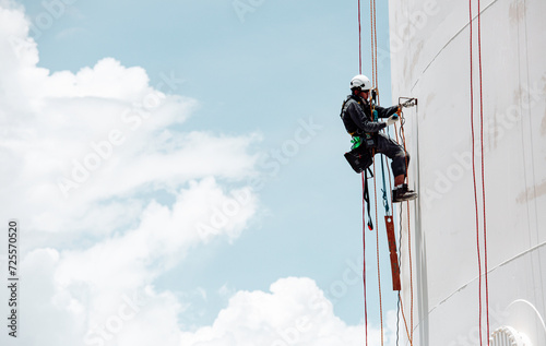 Focus top view male worker down height tank roof rope access safety inspection of thickness storage tank gas photo