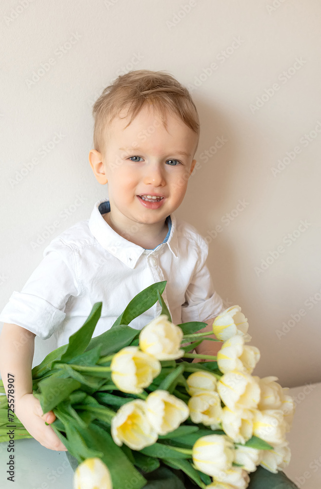 Happy little boy holding a bouquet of white tulips. Mother's day Happy little boy holding a bouquet of white tulips. Mother's day