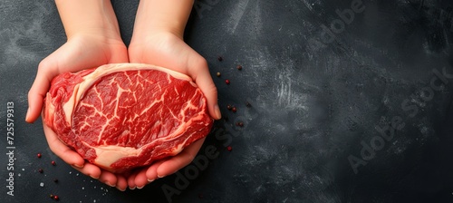 Juicy raw beef steak held by skilled butcher s hands with ample copy space for text placement photo