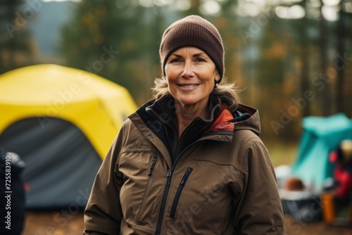 Portrait of smiling senior woman standing in front of tent at campsite