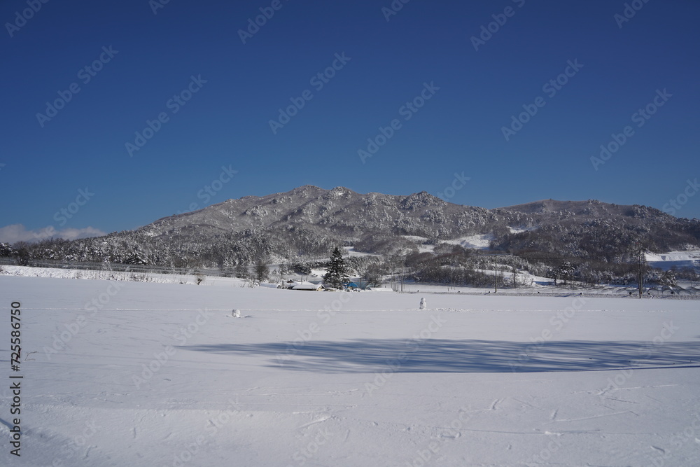 Scenery of a rural village surrounded by mountains covered in white snow.