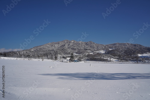 Scenery of a rural village surrounded by mountains covered in white snow.