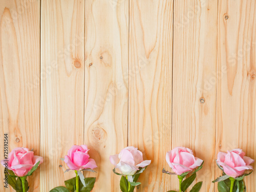 Artificial pink rose on wooden background