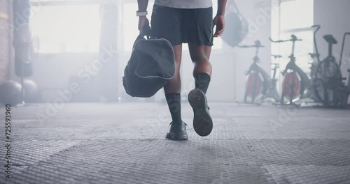 Person, athlete and walking with bag in gym for boxing challenge for competition, physical activity or wellness. Legs, shoes and muscle in training for fight workout or exercise, confident or health photo