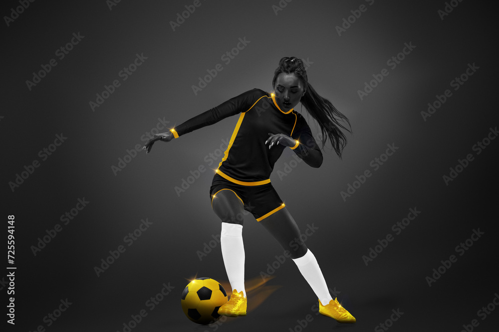 Obraz premium Young woman, soccer playing in motion during game, dribbling ball over dark background. Yellow elements. Monochrome. Concept of competition, tournament, match, game. Creative design.