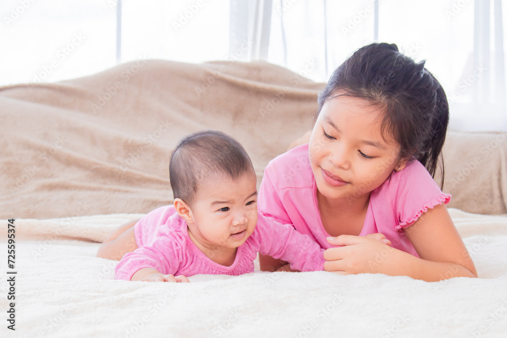 Asian sibling love bonding relationship, adorable girl playing with toddler younger sister on bed soft touching, happy kids nursing hugging embracing together, preschool girl spend holiday at home Asian sibling love bonding relationship, adorable girl playing with toddler younger sister on bed soft touching, happy kids nursing hugging embracing together, preschool girl spend holiday at home