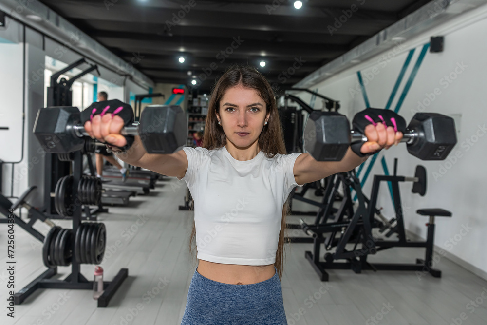 Caucasian  athletic fitness instructor doing exercises in her arms biceps with dumbbell at gym