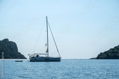 Greece summer vacation. Moored luxury yacht in calm sparkle light blue deep Aegean sea water.