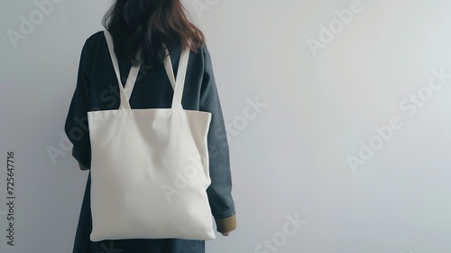 Generative AI : Urban mockup of tote bag. Girl holding white cotton tote bag on a white wall background. Template can be used for you design