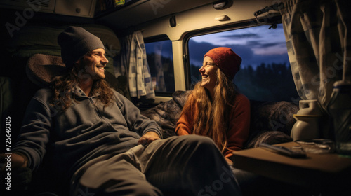 Couple sitting in camper van at night. They are looking at each other and smiling