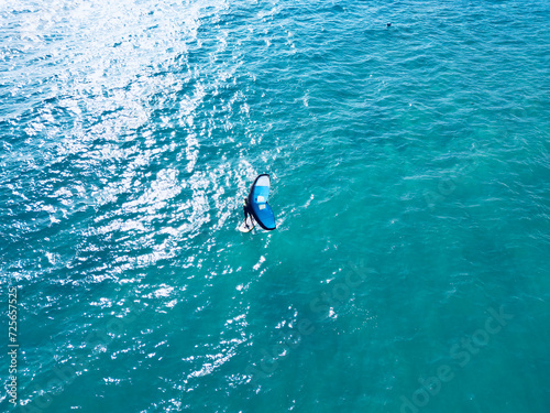 Photography Aerial view of a tourist enjoying wingfoil surfing on the beach.