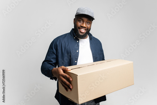 An approachable young African-American man delivers a package with a welcoming smile, creating a scene of friendly and efficient service photo
