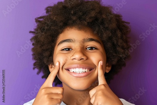 a young boy smiling with fingers on cheeks