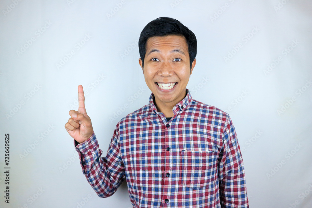 Asian man smiling while pointing up presenting product. advertising concept