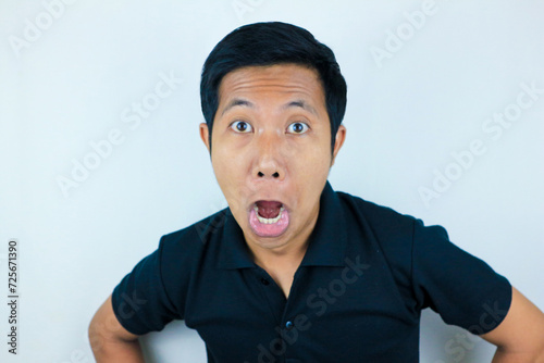 funny expression of shocked and surprised Asian man wearing a black t-shirt looking at the camera photo