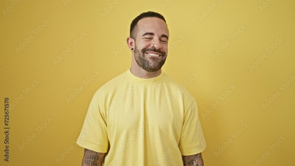 Portrait of a smiling bearded man in yellow shirt isolated against a yellow background Portrait of a smiling bearded man in yellow shirt isolated against a yellow background