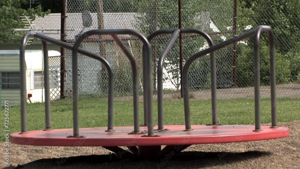 An empty carousel spins in a playground.