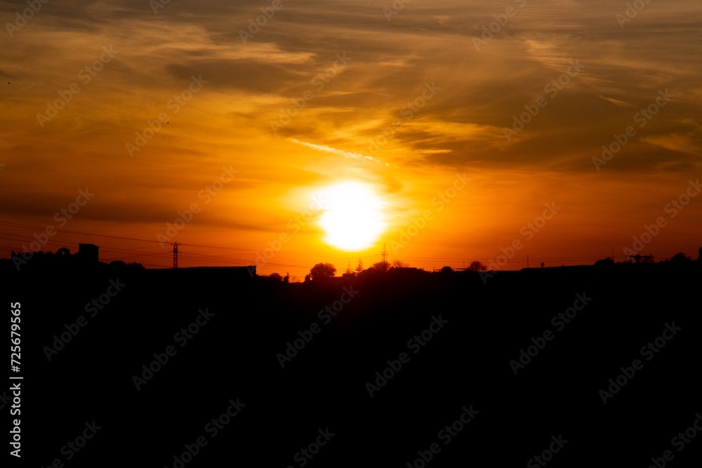 Orange and red sky backlit by trees at dawn or dusk in a rural area Orange and red sky backlit by trees at dawn or dusk in a rural area