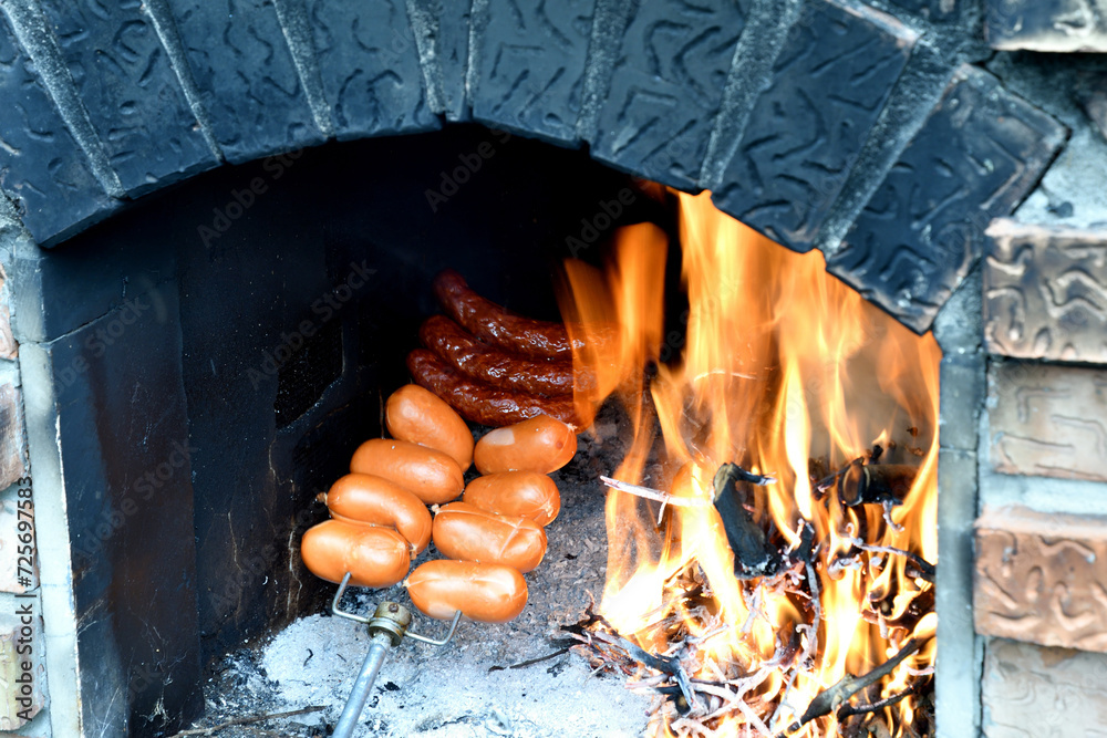 Detail on the roasting sausage on natural fire at cottage in home fireplace at grill party