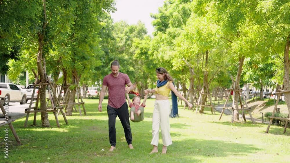 Caucasian father mother hold their little son hand, holding each child's hand lifting up, father mother take their adorable son for walk in picnic park on nice, sunny day, three feet touched grass. Caucasian father mother hold their little son hand, holding each child's hand lifting up, father mother take their adorable son for walk in picnic park on nice, sunny day, three feet touched grass.